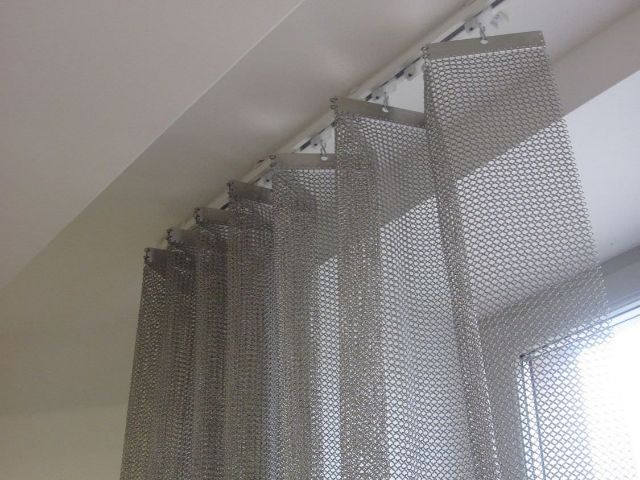 The folding chainmail curtain is hanging on the curtain rod.