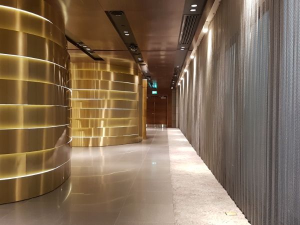 O lobby do hotel está decorado com colunas douradas e cortinas de metal prateado.