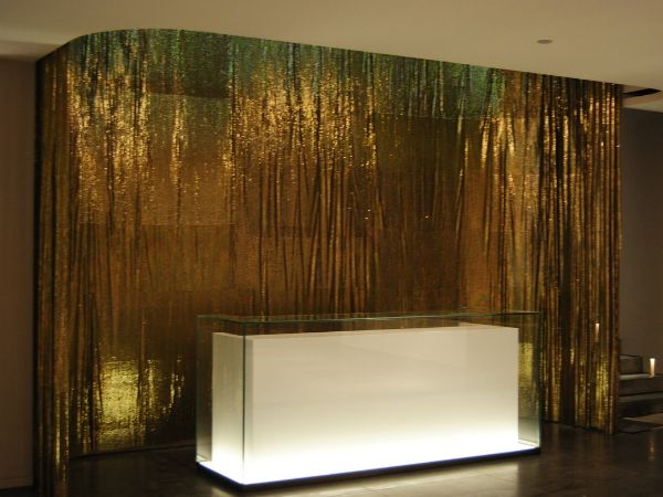 Le hall de l'hôtel utilise un tissu métallique comme toile de fond de la réception.